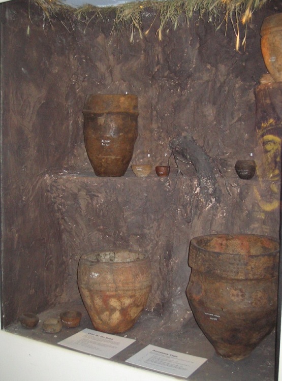I think these are Bronze Age Collared Urns, displayed at the depth they were discovered in different mounds. The detailing on the pottery is superb.
