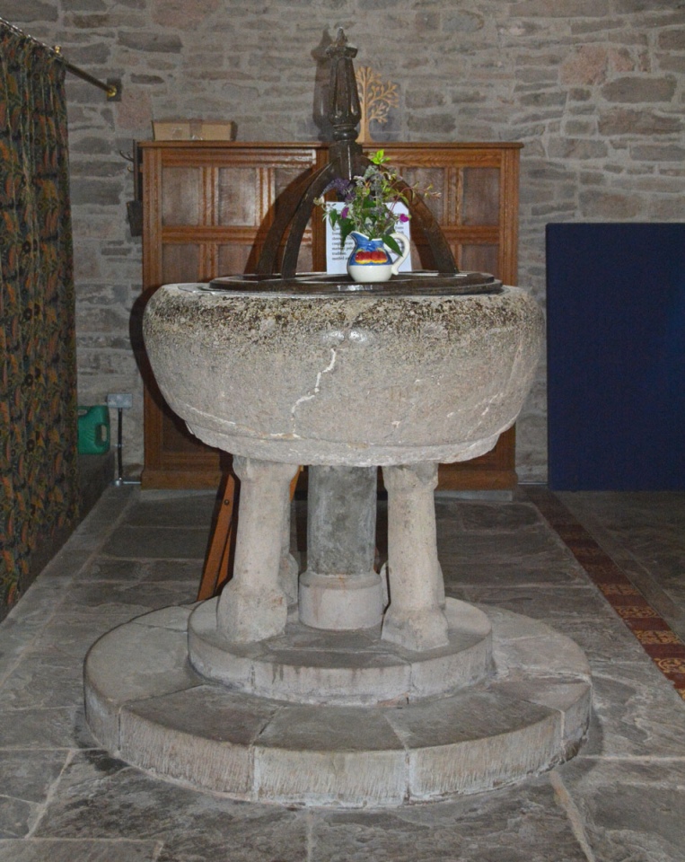 The early Norman font at the western end of the church, just inside the south door.  It stands on three comparatively thin legs, which look as if they may not bear the considerable weight of the bowl (but they do!). The sign on top of the font reads: 