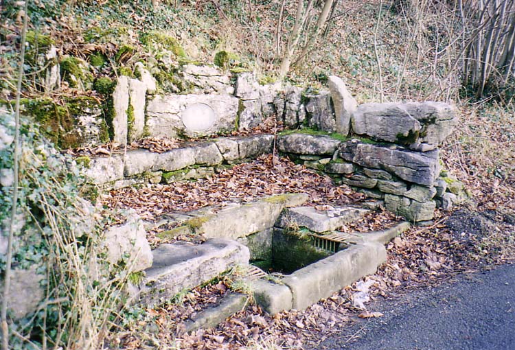 Blocks of the local limestone form a wall, with a welcome seat, around the well.