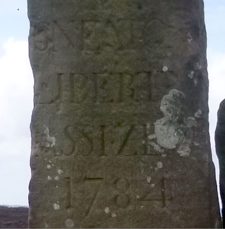 Close up of engraving on the east face of the taller stone, August 2015. It says over four lines SNEATON / LIBERTY / ASSISE / 1784. The first letter on each of the lines has eroded or is eroding away.