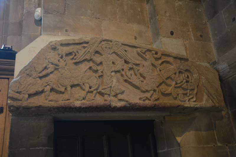 The front face of the tympanum, thought to come from the original Saxon building, which sits above the door on the west wall of the north transept.  The carving shows St Michael warding off a dragon and is said to date from 1100.