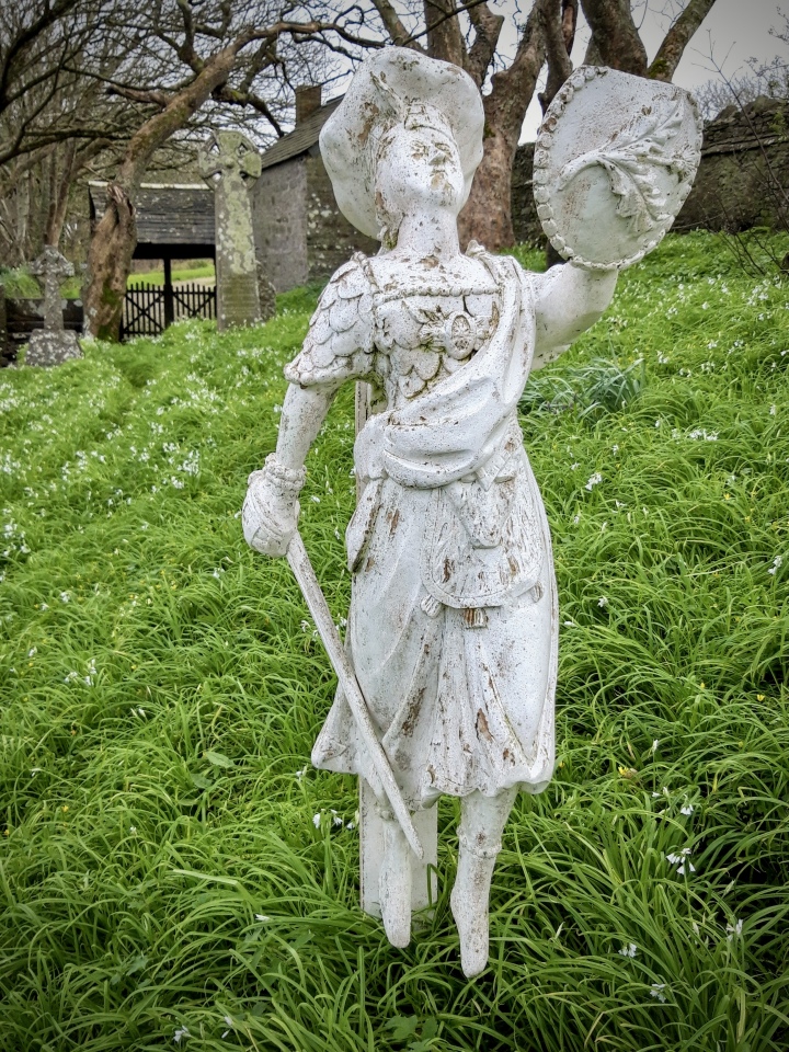 April 2004. The listed churchyard cross is visible in the background of this photograph (on the left, near the lych gate). The main subject of this photo is a resin replica of the figurehead from the ship Caledonia (of Arbroath) which was wrecked off the coast near Morwenstow in 1842. Only one of the crew survived the shipwreck. The bodies of most of the deceased were recovered and the vicar Rev H