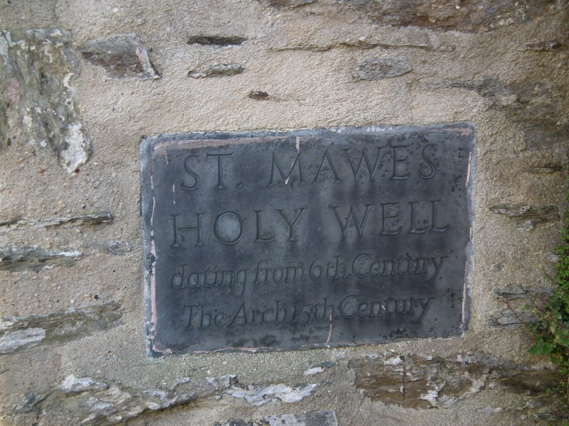 The plaque on the adjacent wall telling the age of the well and arch.