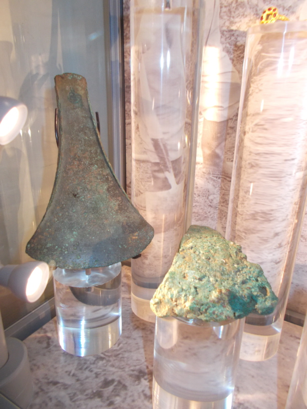 A 'Flat Axe' on display in the cabinet in the foyer of Torquay Museum with the Milber Camp figurines.  It is described as 'Early Bronze Age' and from 'Broadsands, Churston', and 'made from copper or bronze'.
