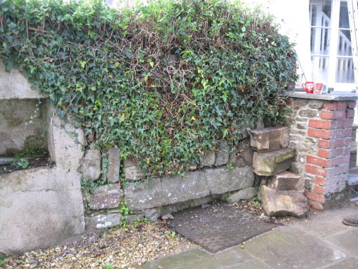This shot shows the 'new' well to the left, with the original well underneath the metal cover, with the old walling covered in ivy, above it.  According to the builder working nearby, the council are going to reinstate the original well soon.