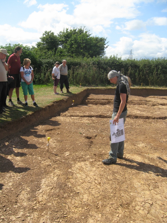 Our excellent guide stands at the southern end of the dig area, holding a site survey.  I forget what he was saying here!  (Was hoping to enlarge that plan!  The next shot shows it better.)