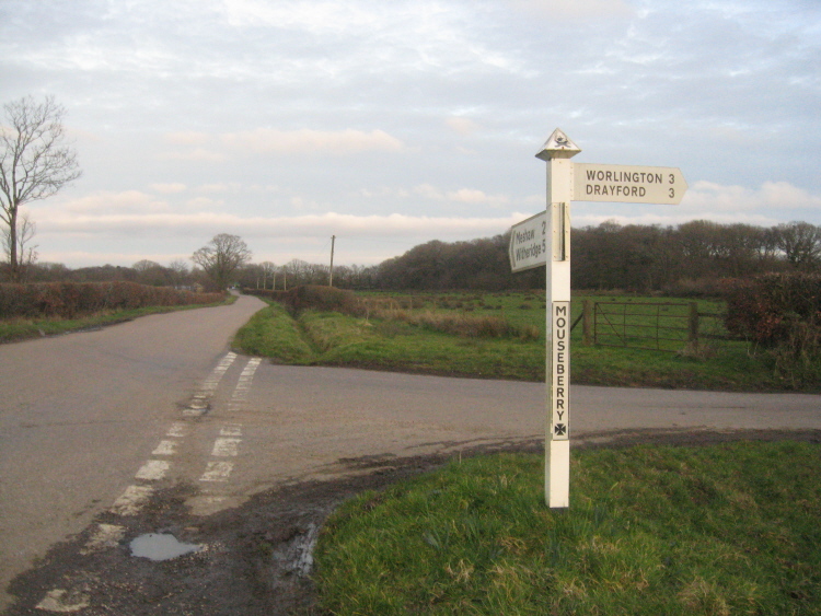 The sign post at junction of Chulmleigh road and Mouseberry, right opposite the gate where the round barrow lies.  (Looking back towards Burrow Cross.)