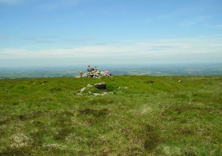 Cosdon Hill Summit Cairns, Dartmoor, Devon SX636915 to SX637917

The remains of five cairns can clearly be found at the summit of Cosdon Hill. 

The fifth cairn at the north of the hill is a very impressive beast. The outer edges of the cairn are nicely held in place by a ring of large stone slabs, and within the cairn structure itself can clearly be made out a further two or perhaps three con