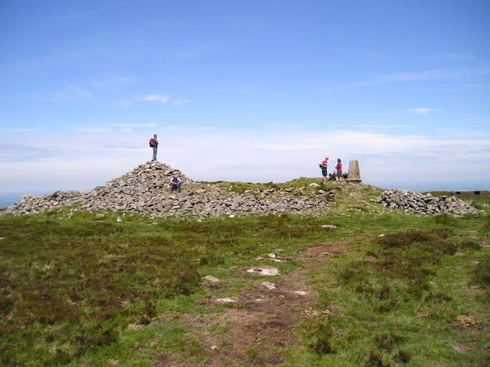 Cosdon Hill Summit Cairns, Dartmoor, Devon SX636915 to SX637917

The remains of five cairns can clearly be found at the summit of Cosdon Hill, approximately following the ridge of the hill in a north-south manner. 

Starting at the south, on the summit, the first cairn is a massive, but much altered structure, up to 3 metres high and 25 metres diameter, which incorporates a trig point and seve