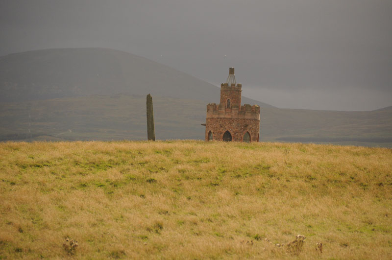 The Hurl Stone is the sharp 'needle' to the left of the modern tower, which was built by the landowner in 2000.  As there are no public footpaths to the stone, I have written to ask for permission to walk across the field to take close up photographs.  