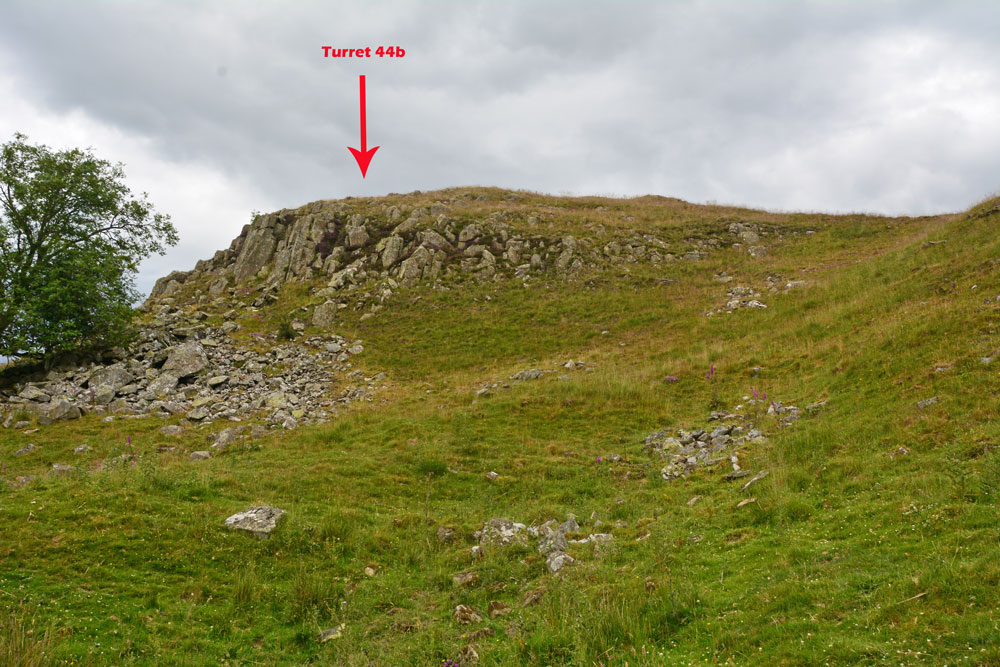 Turret 44b is at the top of the eastern crag of Walltown Crags. The red arrow marks its location. In the dip below, the remains of the wall continue east-west as a stony bank. The 'nick' above which the turret sits is home to King Arthur's holy well. Photo by Andrew T