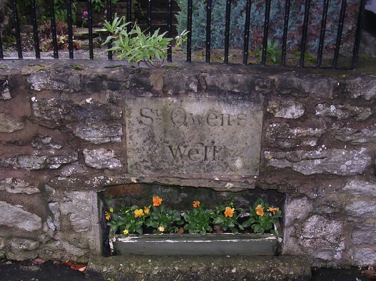 The not very impressive remains of St Owen's Well at Much Wenlock. At least there is a record of it here, though.

A small ledge under the plaque holds a tub of violas; the only beautifying object left here on the spot.

See the main site entry for details. (Link to left of picture).
