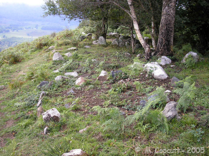 Several of the smaller Lou Couraus Cromlechs, seen together on their mountain lookout. 
The nearest is a double ring, the outer ring made using white stones, the inner ring made of black stones. 