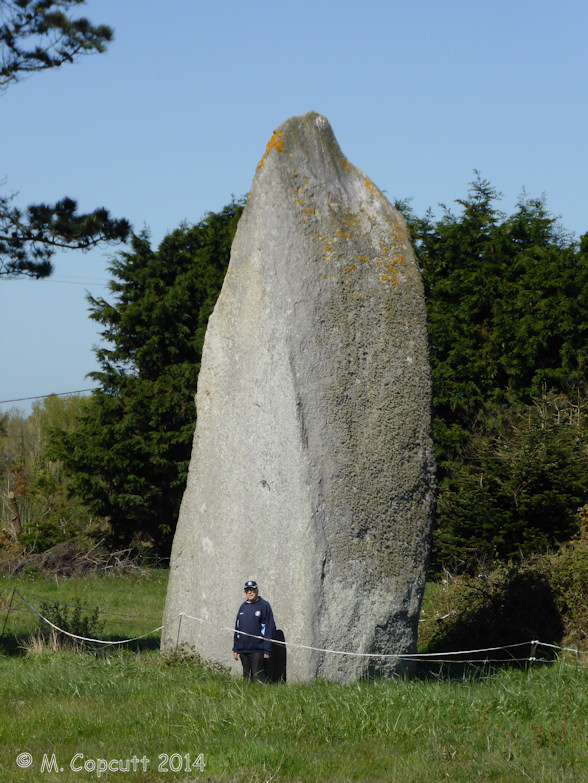 The menhir must be about 8 metres in height, of large girth at the bottom, slowly tapering up to a pointed top.

The southeastern face of the menhir has been worked into an extremely flat surface, of triangular shape, something which clearly took a lot of time to produce. 