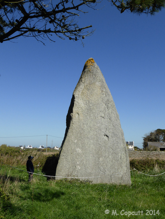 The menhir must be about 8 metres in height, of large girth at the bottom, slowly tapering up to a pointed top.

The southeastern face of the menhir has been worked into an extremely flat surface, of triangular shape, something which clearly took a lot of time to produce. 