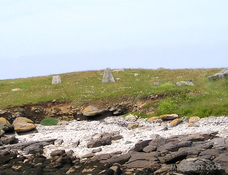 There are remains of at least two menhirs to the south of the island. 
Other larger menhirs were destroyed in the second world war. I would guess an inspection of the rocks on the island would reveal some pieces. 