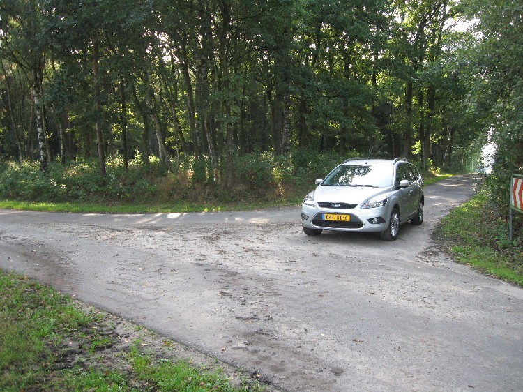 Photograph taken at the corner where Zum Herthum and Herthumstr meet.  Herthum Lähden Tomb II is in the woods across the road and to the left (east) of the car whilst its sister Herthum Westerloh Grab 2 is to the right (west) of the car behind the red and white road marker.  The I ripped my clothes accessing this site due to the many bramble bushes.  September 2009 