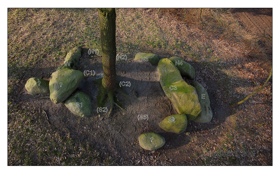 Pole aerial view from the South. 
East-West oriented chamber, measuring appr. 6,5m by 3,5m largely embedded into remains of its barrow. Eastern and western chamber endstones are preserved in situ as well as two orthostats of each longside: N3, N4 and S1 and S4. Three stones marked 