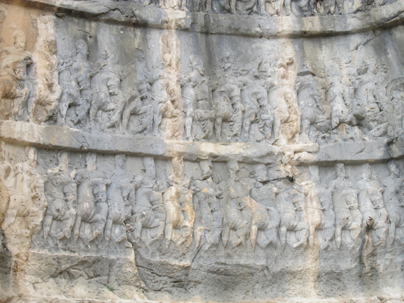 Across the road from the ruins of Bishapur city on the north side of the gorge the first rock carving that you come to is known as Relief III and depicts Shapur's triple victories over Roman armies.  This photo shows a detail from the relief.  April 2014

