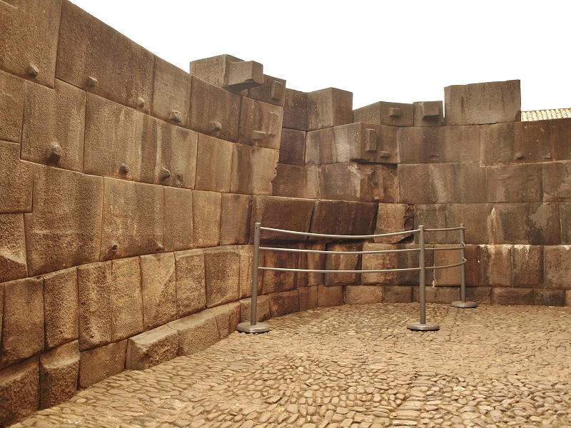 The remains of the Coricancha complex, Cusco. This is the inside the curved outer wall to the west, now surrounding the church of Santo Domingo, Cusco.  The interior curve is considered by some to be the center of all Inca huaca (sacred sites,) an axis mundi.  New Age types can be found here in such numbers that the fence was put up to discourage them from climbing the wall to sit in the alcove.
