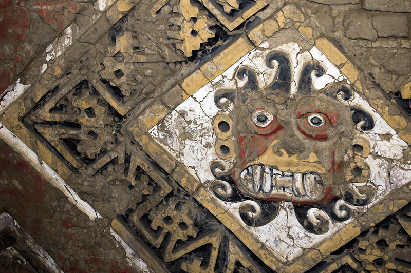 Painted Reliefs on the eroded southern wall of Building B/C.
Huaca de la Luna, Trujillo, Peru.

To create the reliefs featuring the Moche god, Ai Apaec, Moche artists first sketched vertical lines, some 170 centimeters apart, on the walls. Next, they drew diagonal lines forming rhombi in which they placed the disembodied face of the god. The faces are framed by bands of interlocking, geometric 