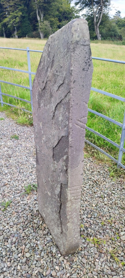 KE065-078006- 

This stone (present location KE065-041004-) stands 1.3m high, and is up to .45m in width and .lm in thickness. Prior to its use as a lintel its inscribed face was damaged, resulting in the loss of all vowel-notches and scores on this surface. The remaining scores along the edge and top of the stone were interpreted by Macalister (1945, 195, no. 201) as: ...MC...GE...M..Q...D...E.