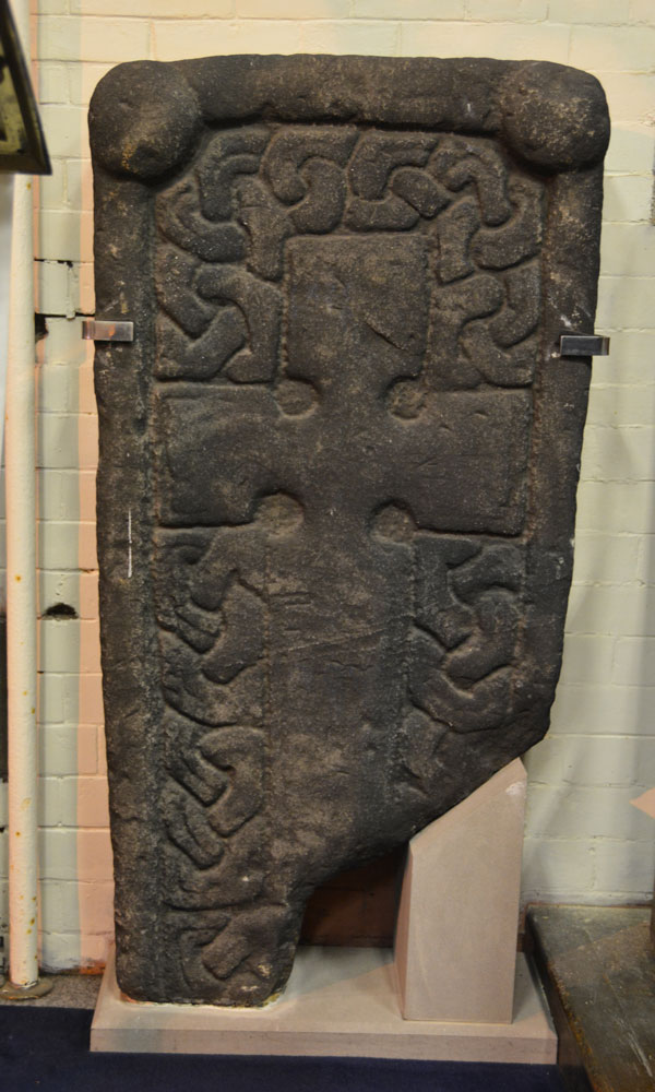 This is Govan 13, displayed in the Baptistry of the church (eastern wall). It is dated to the 10th/11th century.  With a broken base, it measures 1.32m long, 0.68m wide and 0.19m deep. See Canmore 353182. The cross and incised interlacing are particularly deeply carved. The top of the slab has higher relief angle knobs at each corner.