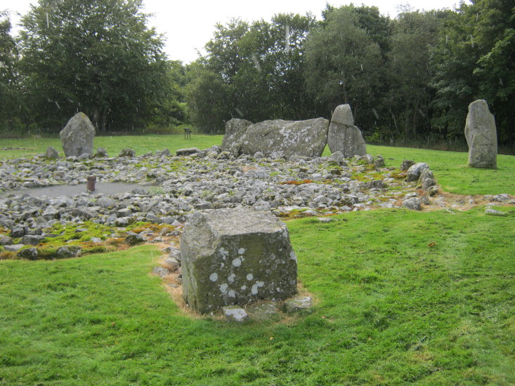 View across the circle towards the now split recumbent stone and its cup marked flanker with the inner cairn stones also visible.  September 2012.