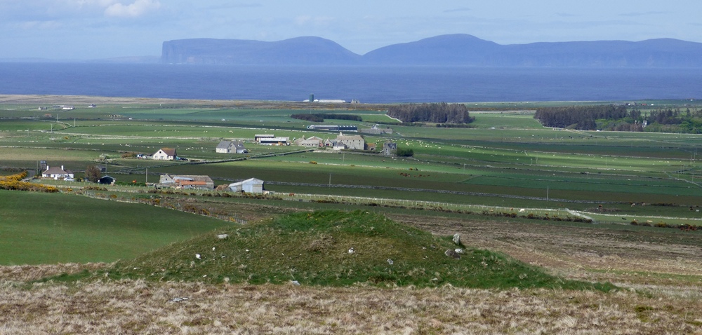 The view of the long cairn from the nearby Na Tri Sithean. Orkney provides a dramatic backdrop.