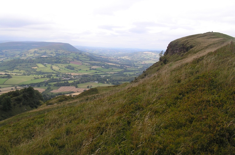 Ysgyryd Fawr, looking north in the direction of Hay-on-Wye, which is best reached via the narrow road via Llanthony and Gospel Pass. 
The enclosure and chapel are at the northern tip, where the trig point can be seen.  
