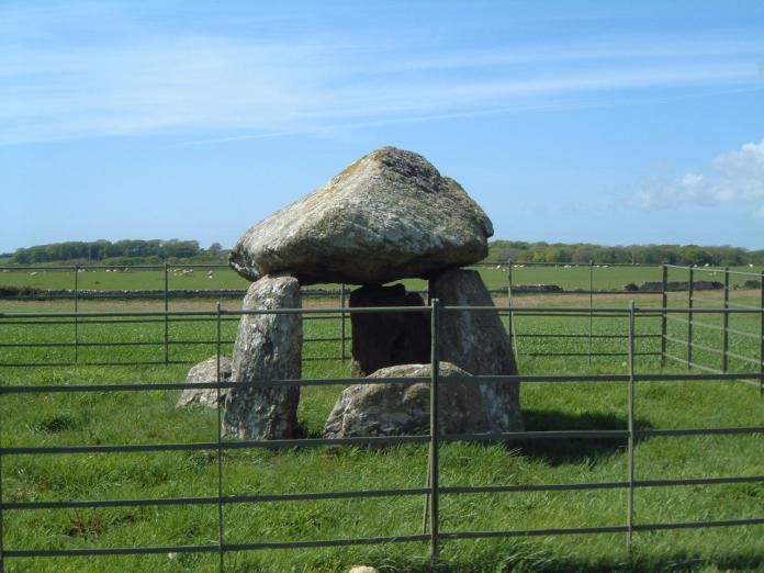 SH 462683
The remains of a simple passage grave. The mushroom-shaped capstone measures 7' x 6'. The low sill stone at the front of the uprights (the eastern end) marks the entrance to the short passage.