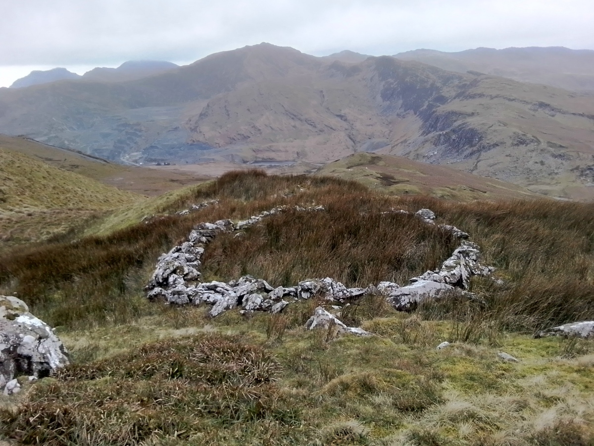 Close up of the hut circle with the summits of the Moelwyns, Allt Fawr and Moel Druman mountains. 