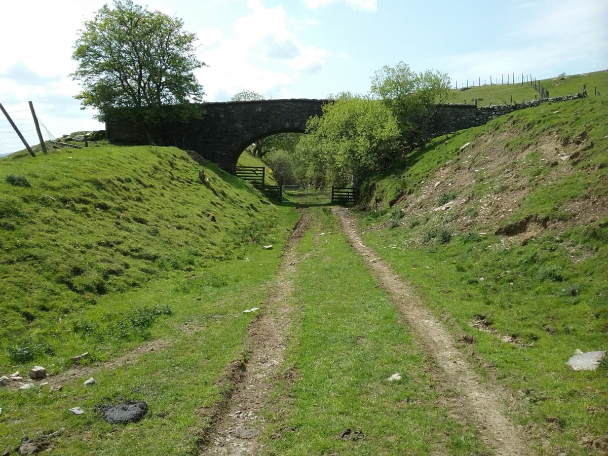 The dismantled railway track with the bridge leading to the field. 