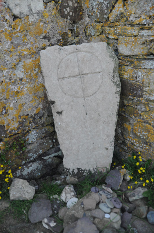 A close up of the cross within the chapel; the offerings and pebbles painted with people's names can be seen at it's base.