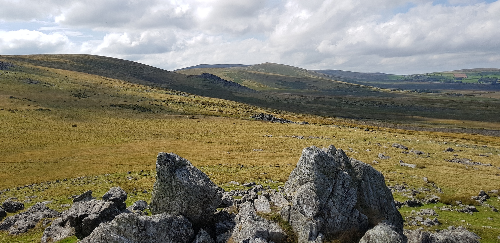 Carn Alw hill fort, this is taken form the southernmost rock outcrop overlooking the the level (habitation?) platform that is visible on the lower right with the grass and the top of the defensive wall running off to the right of the photo.  But on lower left arching to the right, can be seen part of the broad, zone of 'chevaux-de-frise' on the south and southwest of the hillfort.  The eastern sid