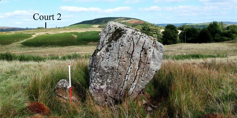 The large stone forming the southern end of the row is pock-marked on its western face. The position of the Court 2 stone row is highlighted.  Originally Court 2 would have been visible on the skyline from Court 1. View from west (Scale 1m).